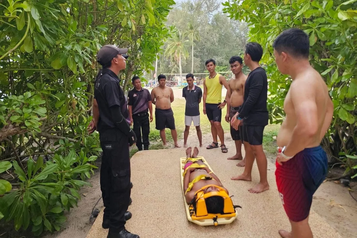 SGS instructor briefing a water-rescue team on stretcher extraction at a Phuket beach